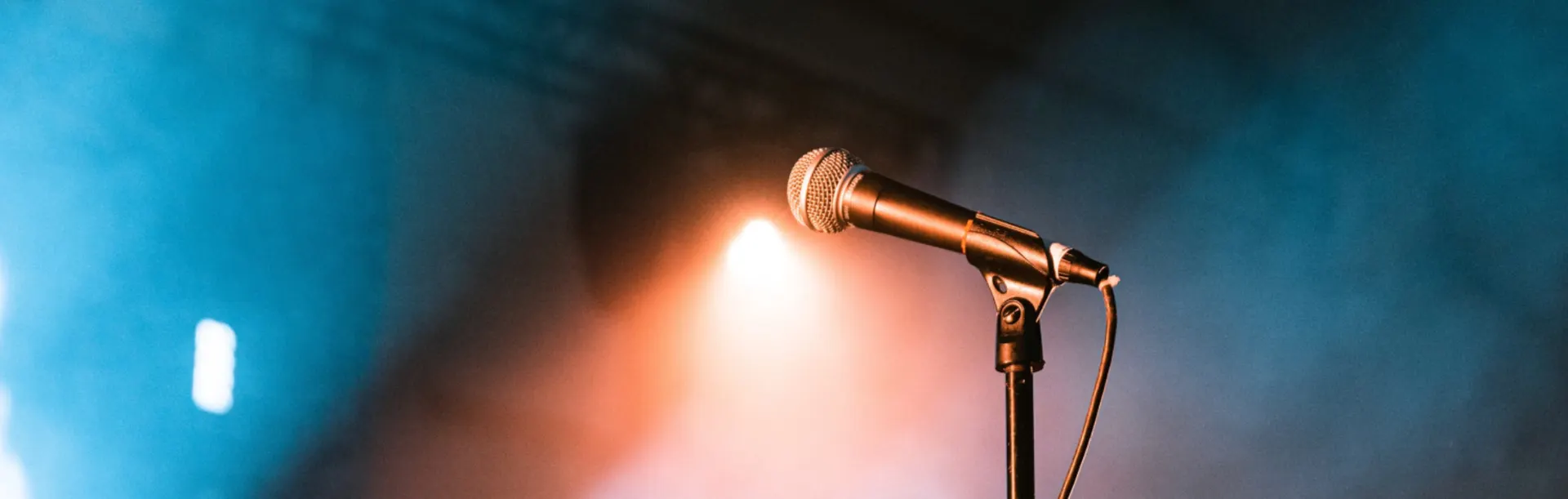 A microphone on a stand under a stage spotlight