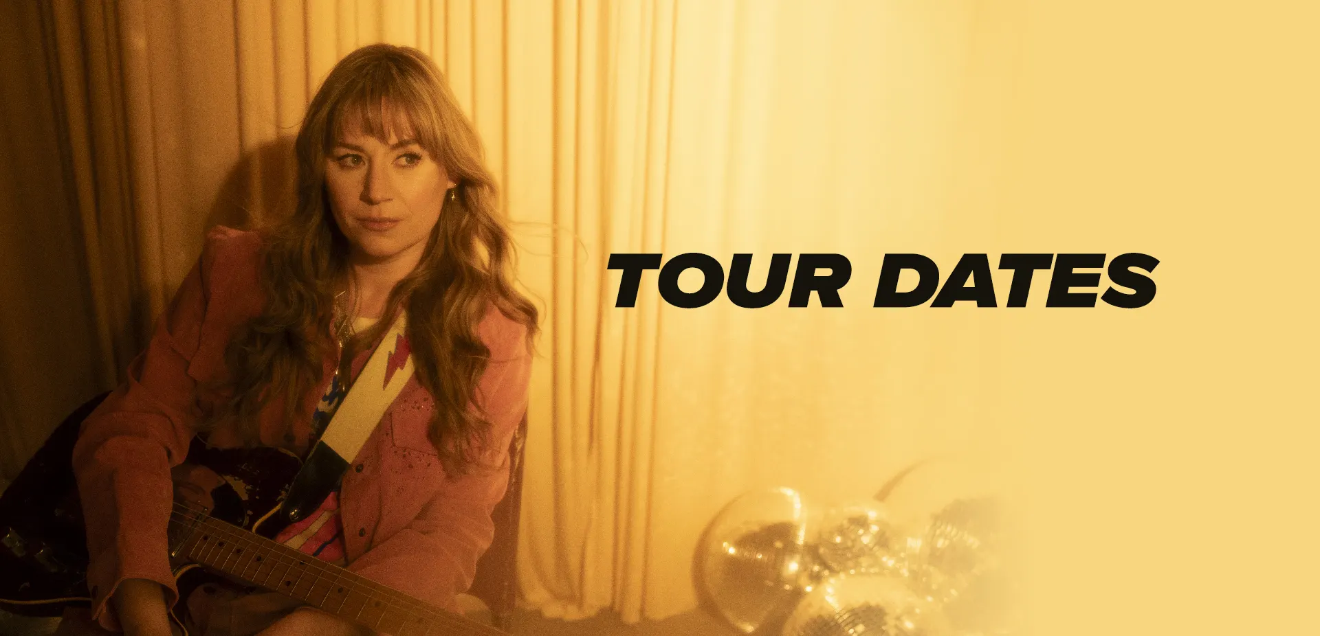 Joanne Shaw Taylor with her guitar against a golden curtain, beside the words Tour Dates