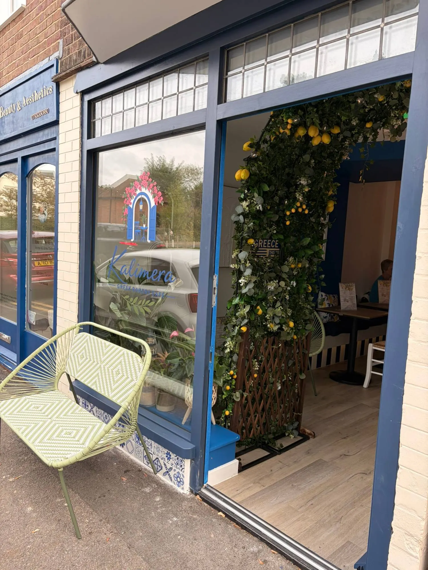 Kalimera's navy shopfront on Leyton Road, with a lemon-hung archway inside the door and a pale green bench outside
